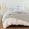 A clean fresh bedroom with white, grey and pink ethical bedding