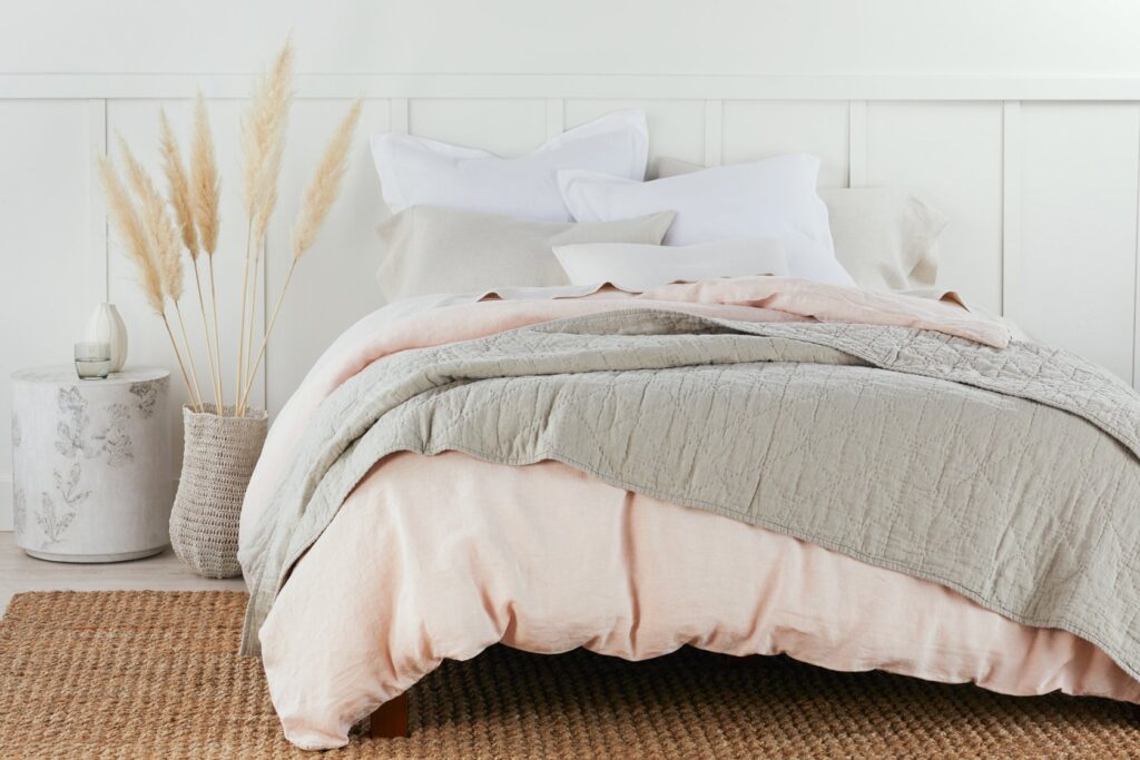 A clean fresh bedroom with white, grey and pink ethical bedding